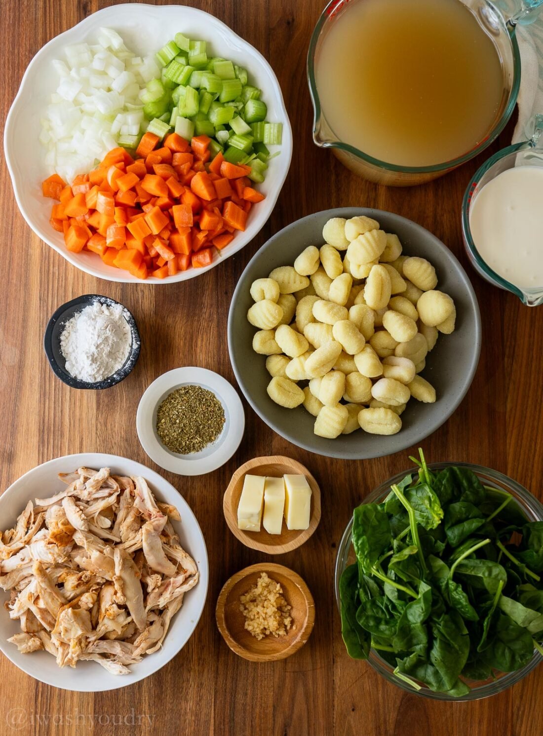 ingredients for creamy chicken gnocchi soup on wooden surface.