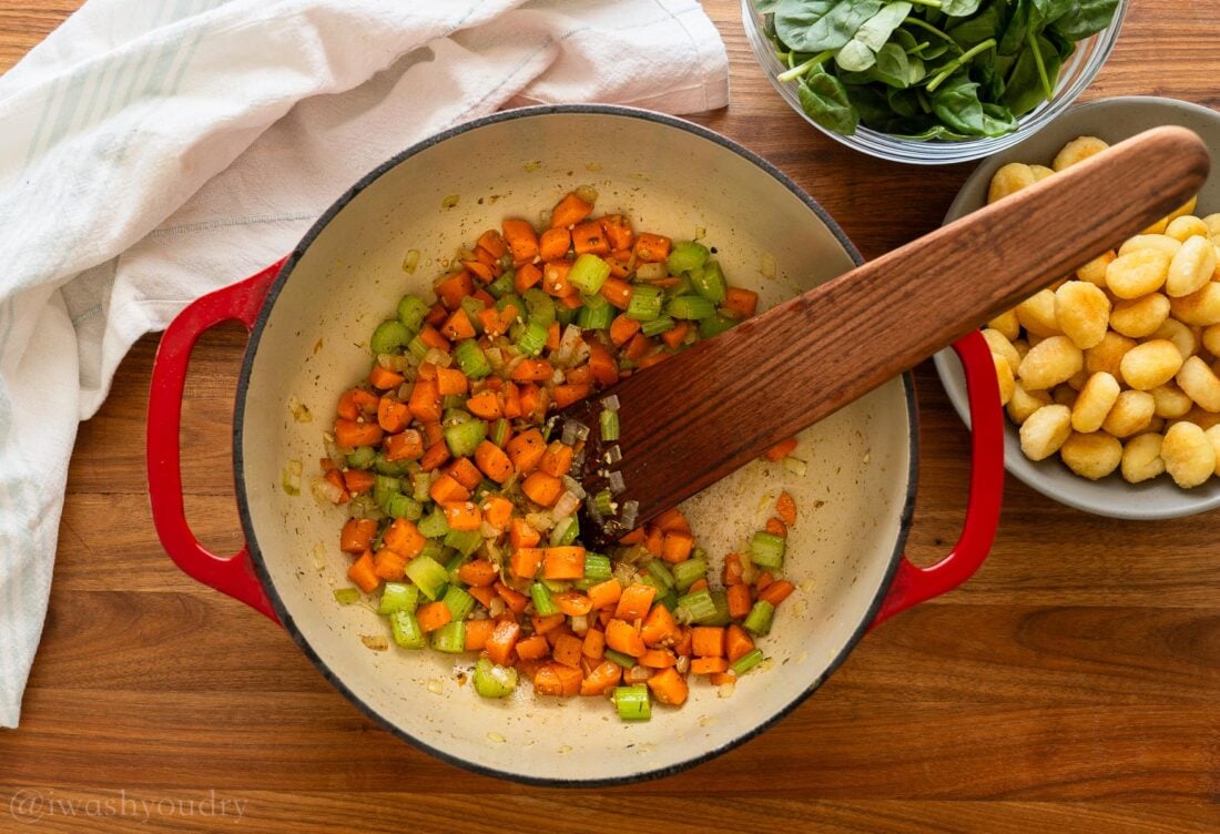 mixed veggies in a red pot with wooden spoon.