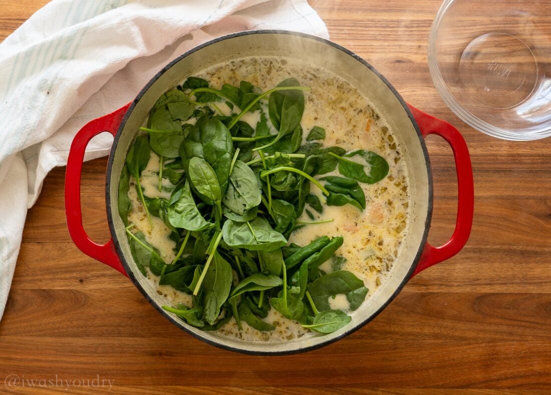 pot of soup with spinach added on top.
