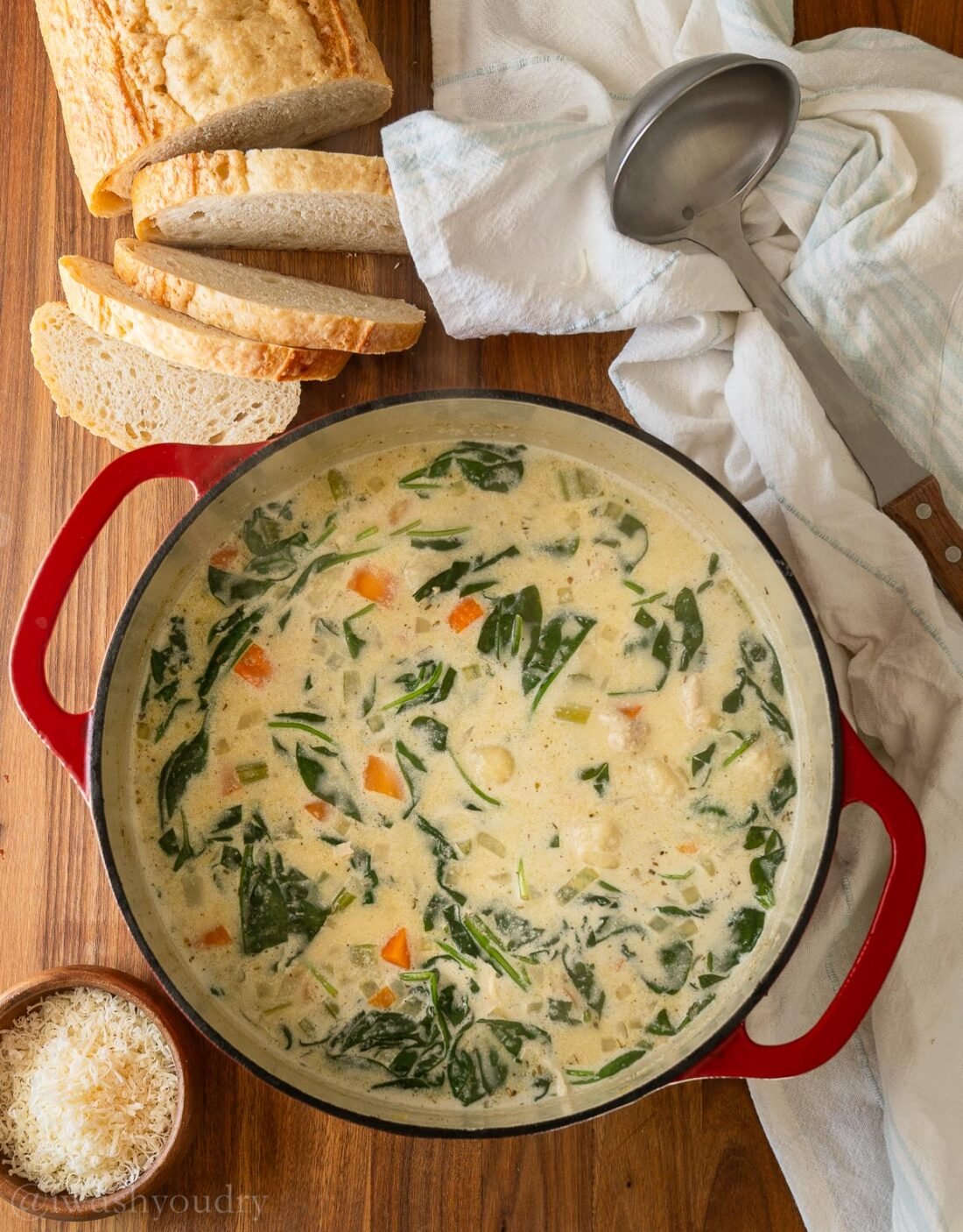 dutch oven filled with gnocchi soup and bread slices on the side.