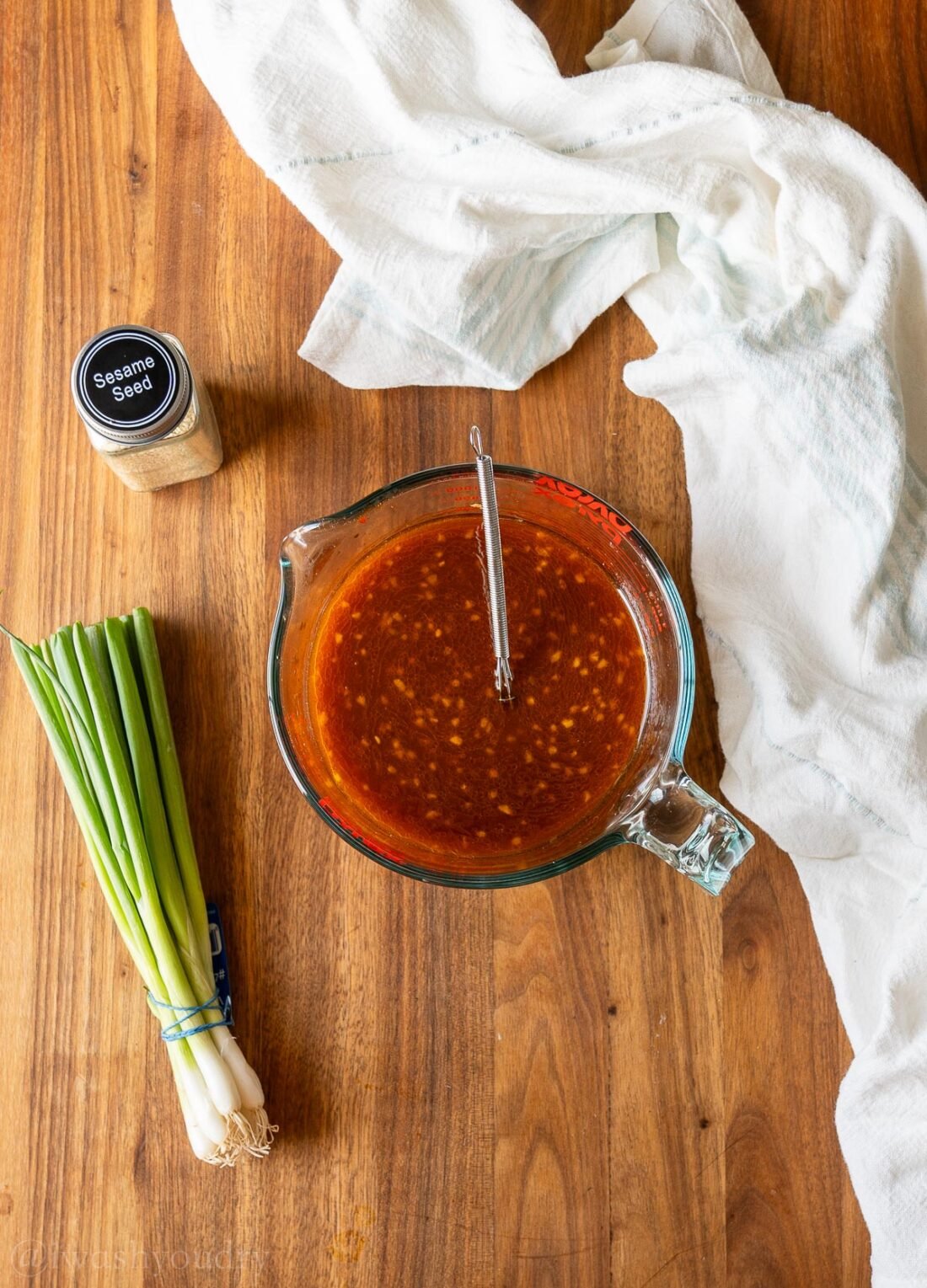 Korean BBQ Sauce ingredients in a measuring cup on wooden surface with green onions.