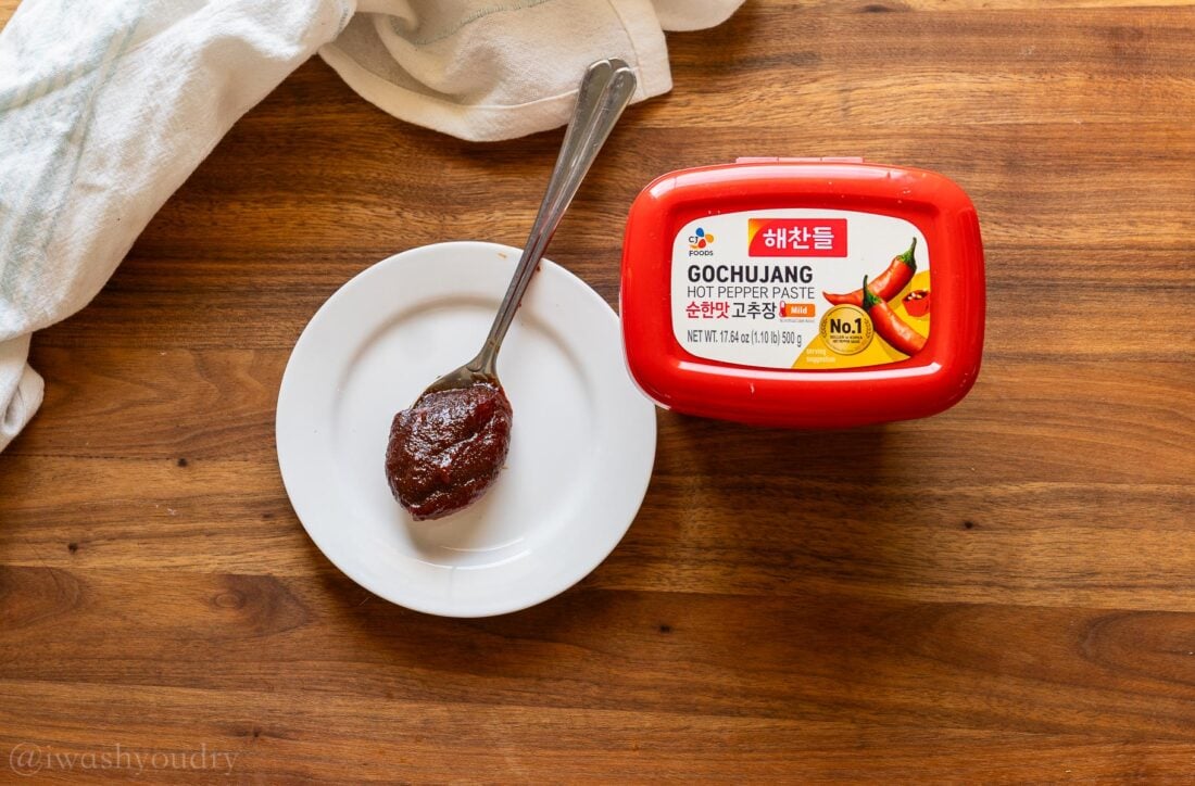 gochujang paste on white plate with red tub next to it.
