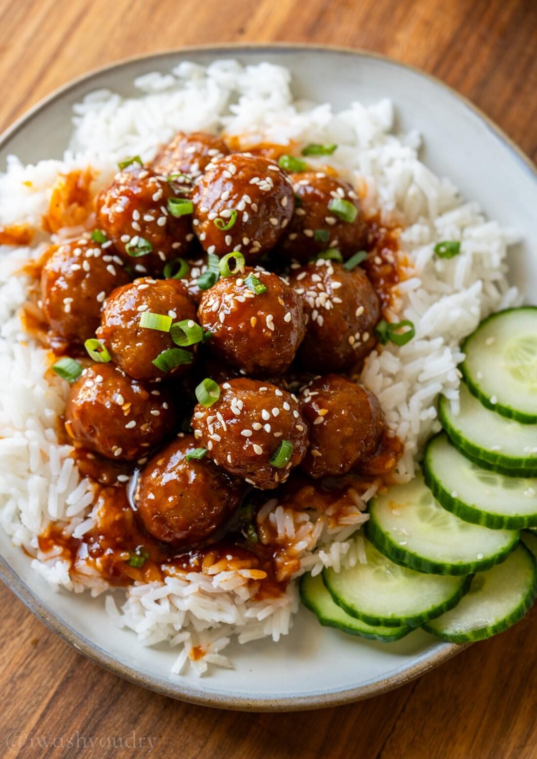 Korean BBQ Meatballs over a bed of white rice with sliced cucumbers.