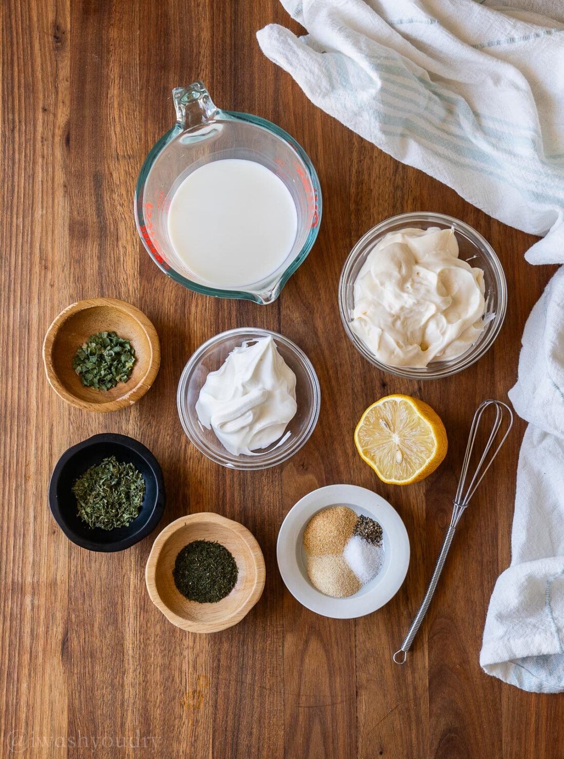 ingredients for ranch dressing with dried herbs on wooden surface.