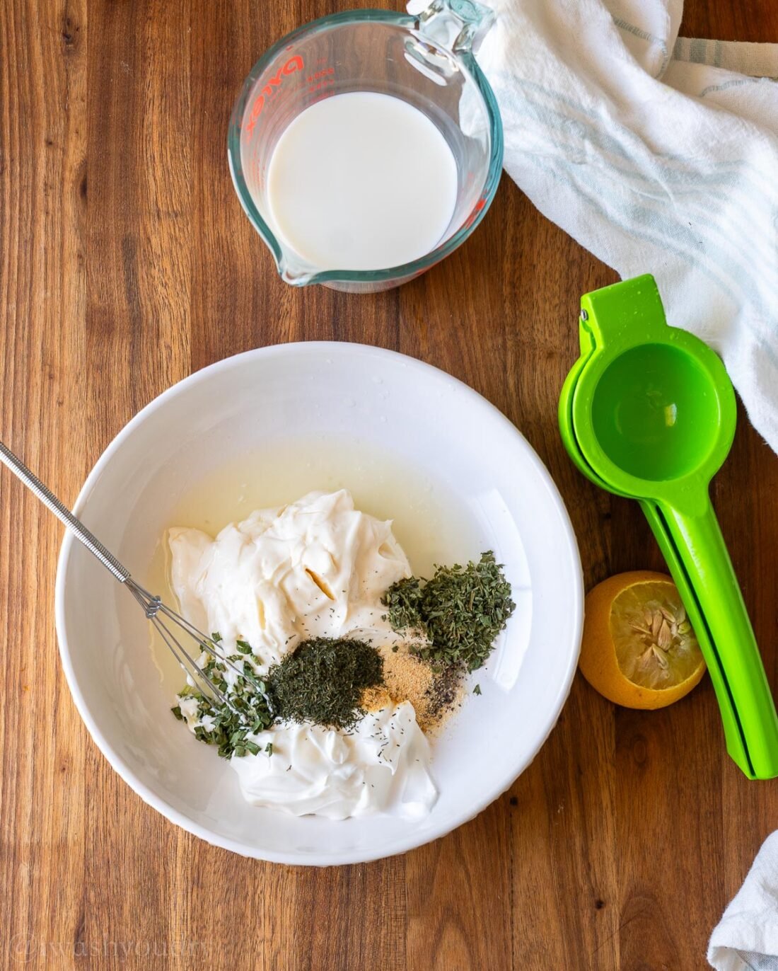 ingredients for ranch dressing in white bowl with whisk.