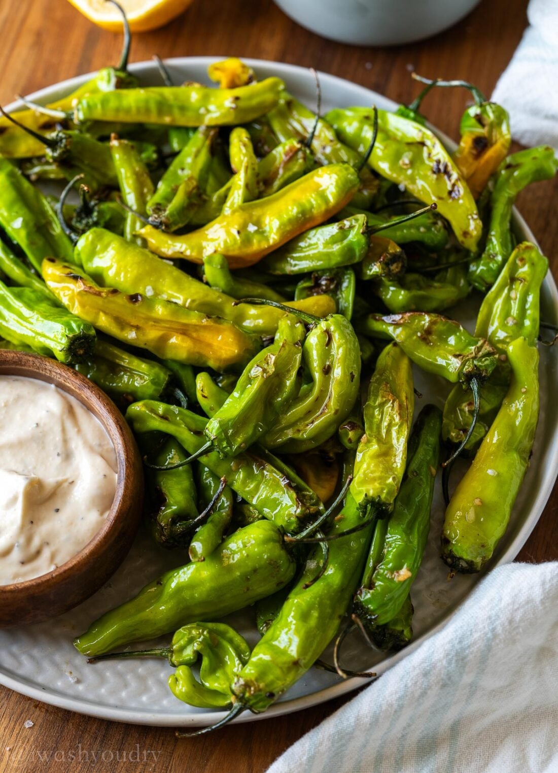 platter of shishito peppers with garlic aioli beside it.