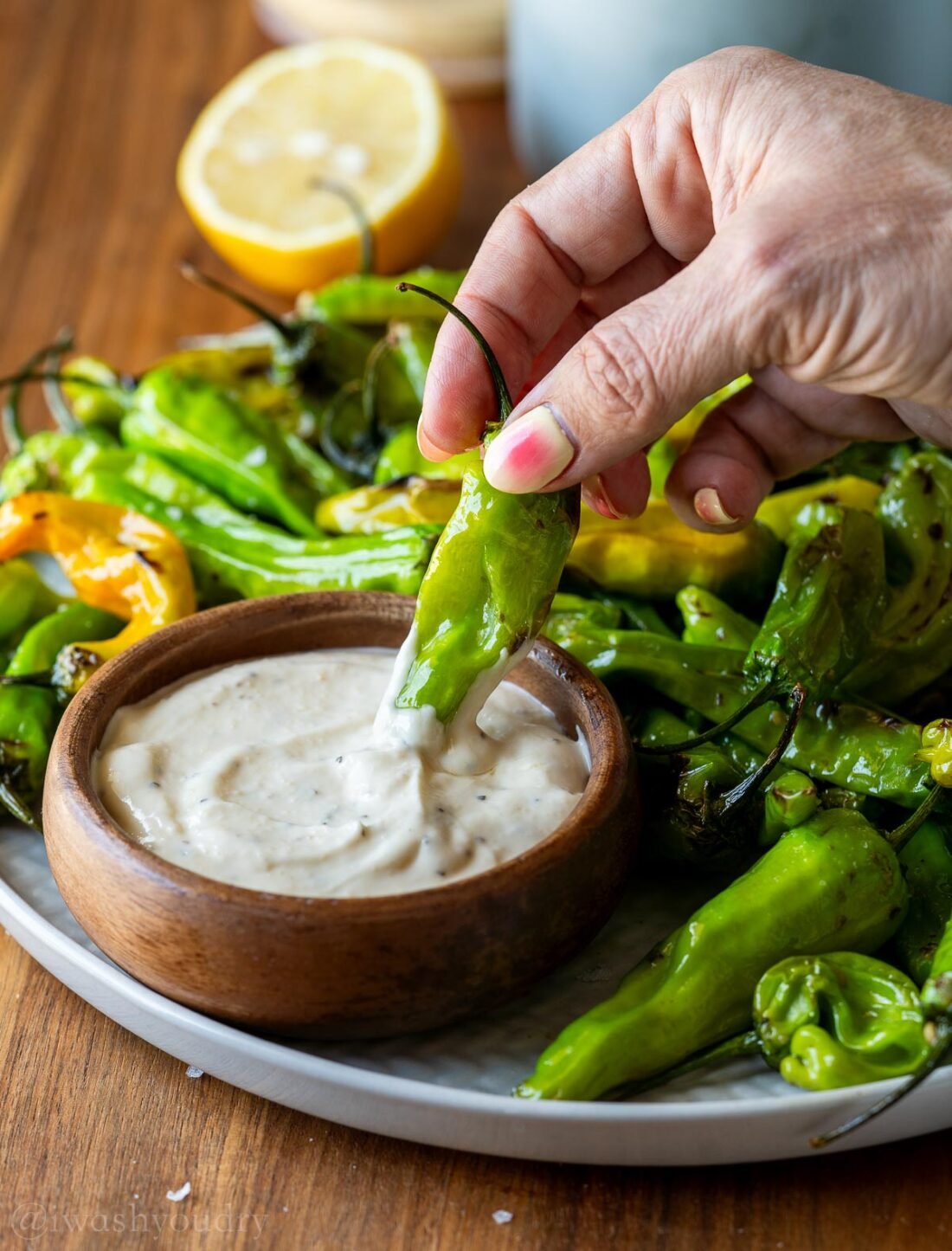 dipping shishito pepper in garlic aioli
