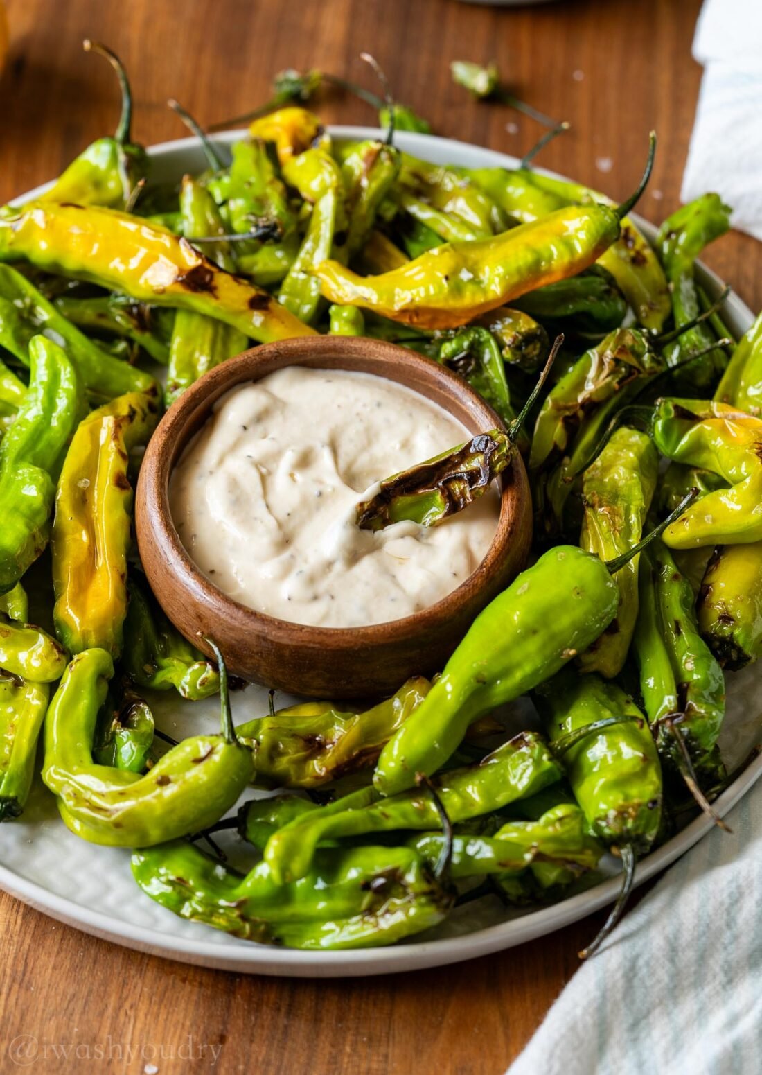 platter of shishito peppers with a bowl of garlic aioli sauce in the middle.