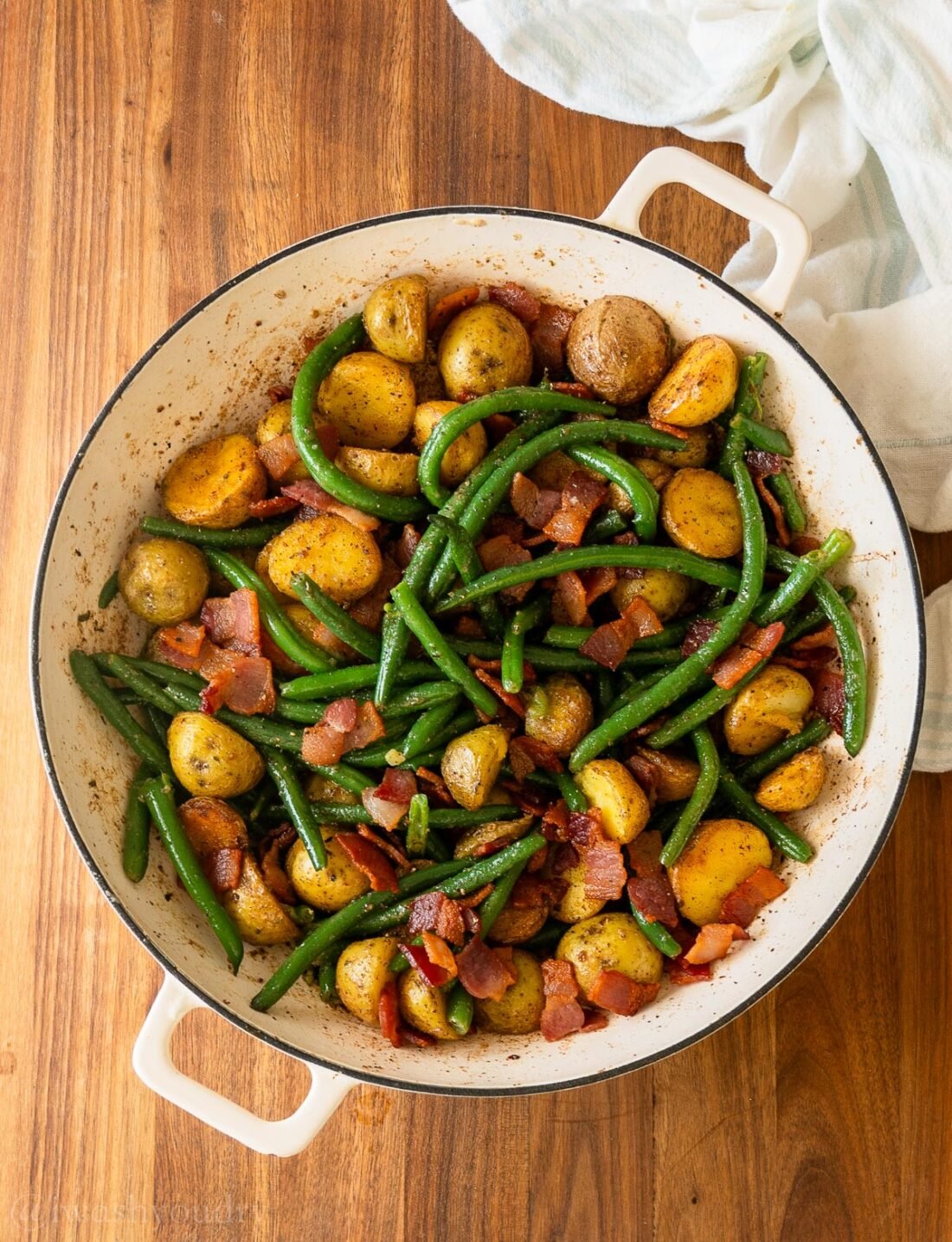 skillet filled with roasted potatoes, green beans and bacon.
