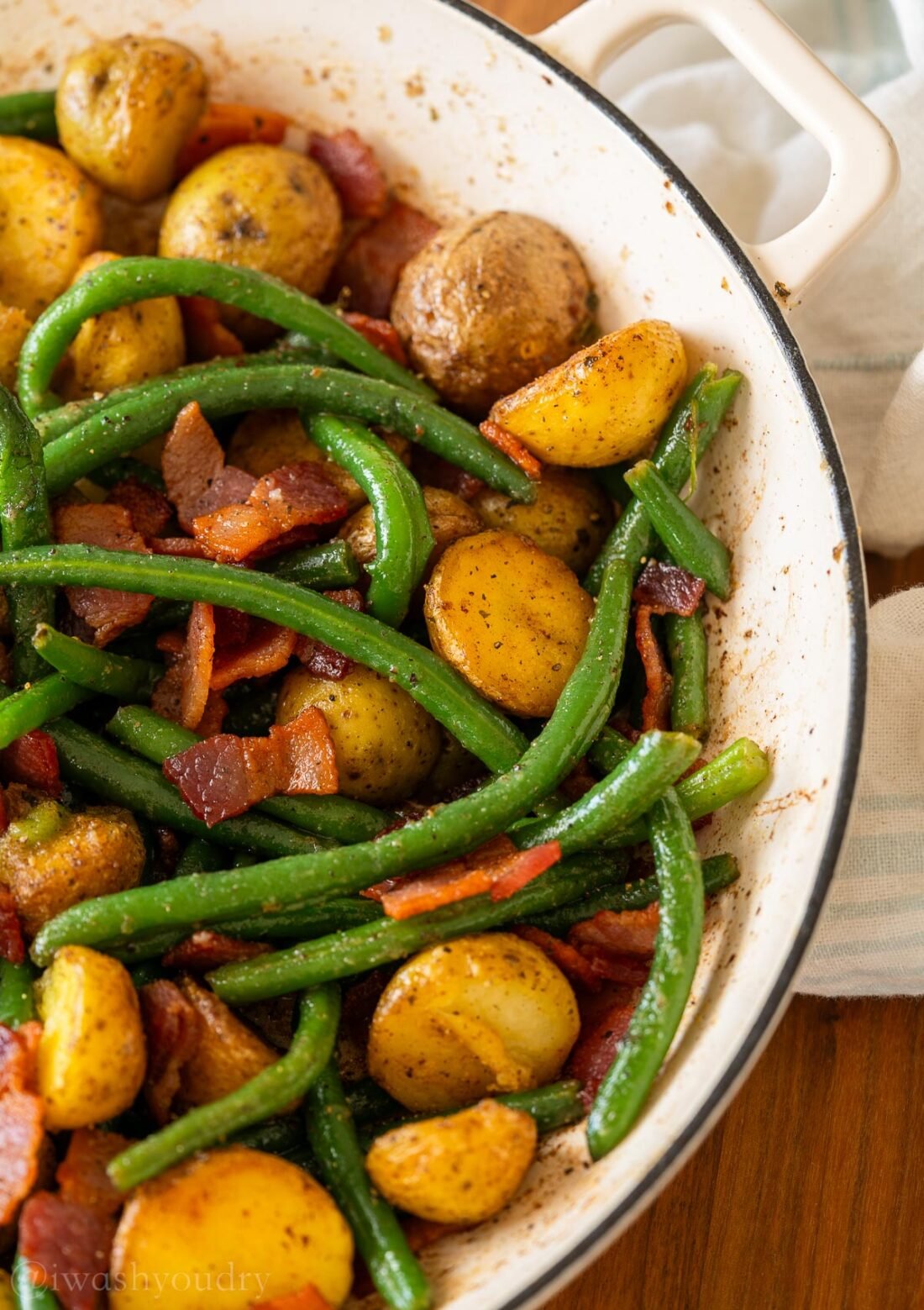 green beans coated in ranch seasoning mix, bacon and crispy fried potatoes in a white pan.