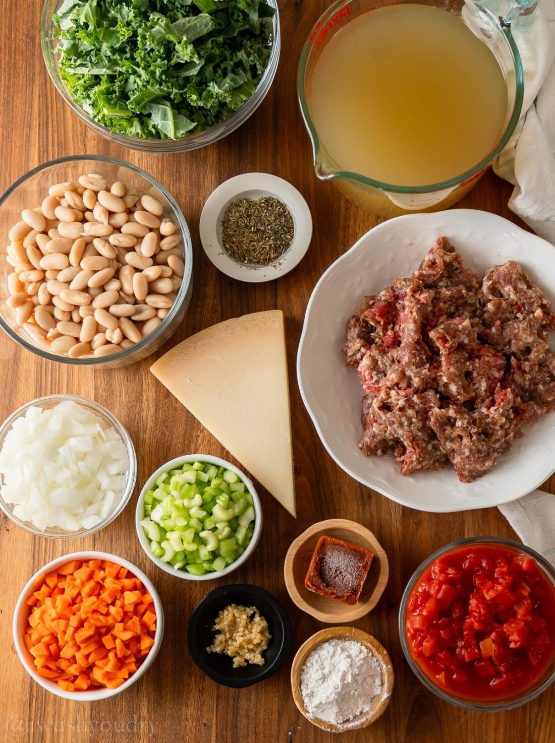 Ingredients for soup on wooden surface with white beans and kale.