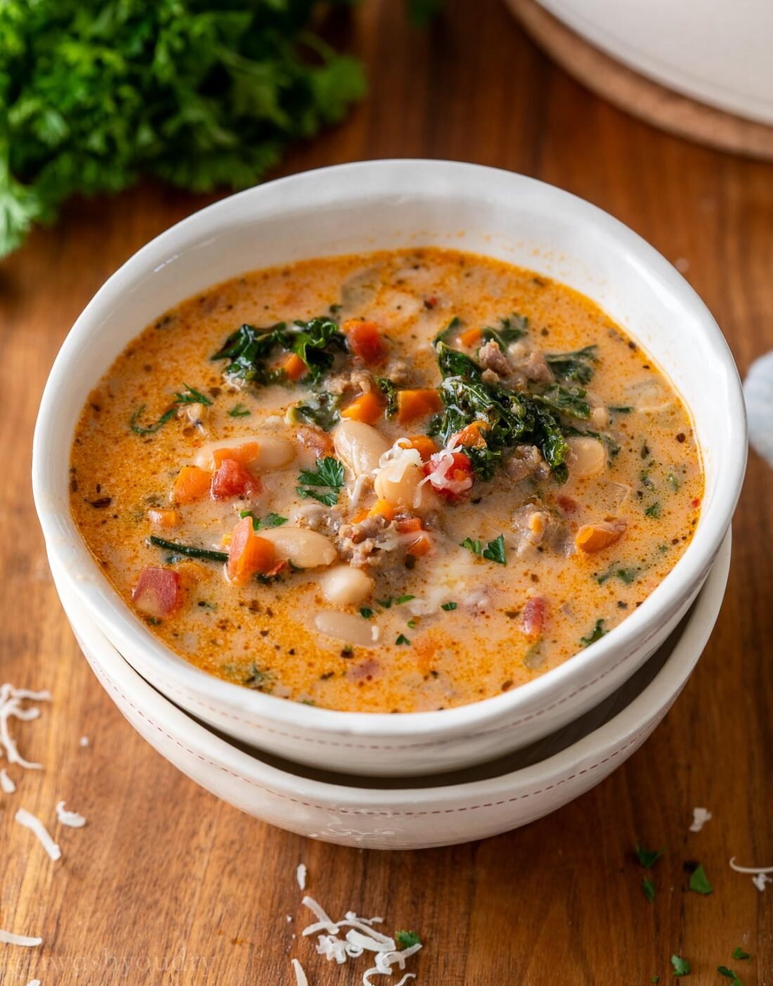 bowl of soup with white eans and kale and tomatoes.