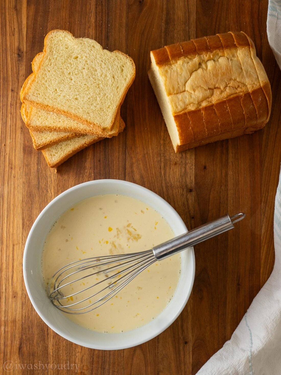 cut up bread and bowl of french toast batter on wood cutting board