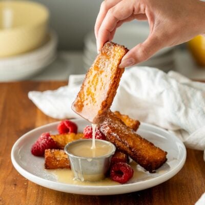 French toast stick dunked in buttermilk syrup on white plate