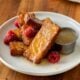 French Toast sticks stacked on a white plate with buttermilk syrup next to it