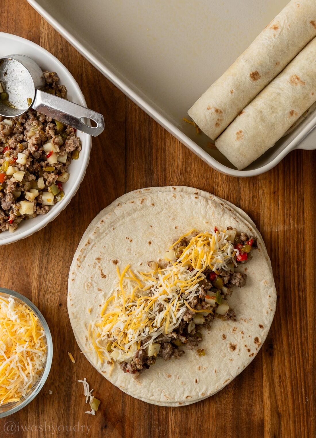 breakfast enchiladas being filled with sausage and cheese.