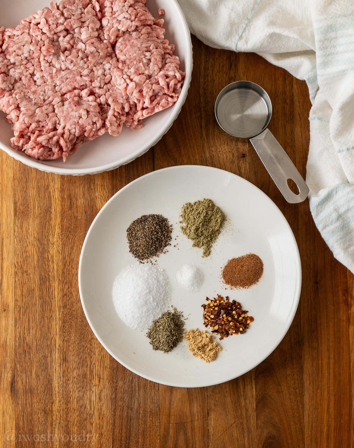 Ingredients for breakfast sausage with the spices on a white plate.