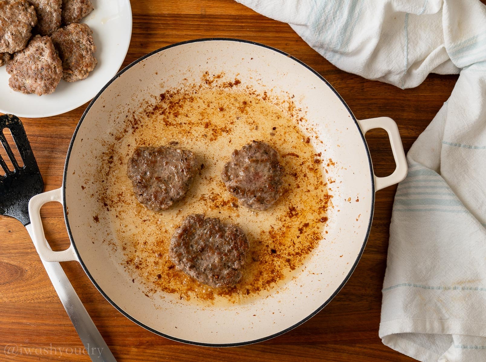 browned sausage patties in skillet with spatula nearby.