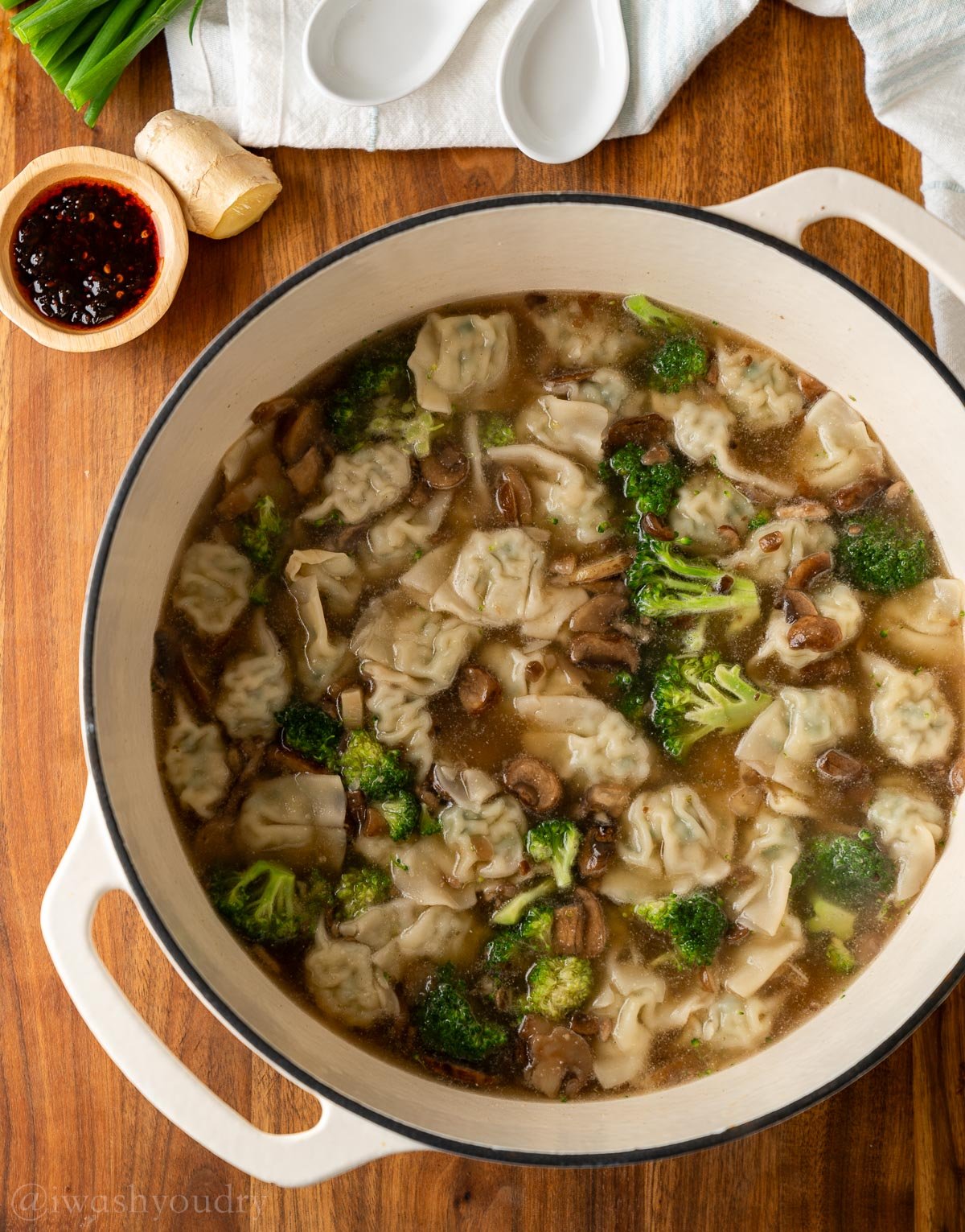 dutch oven filled with wonton soup with mushrooms and broccoli.