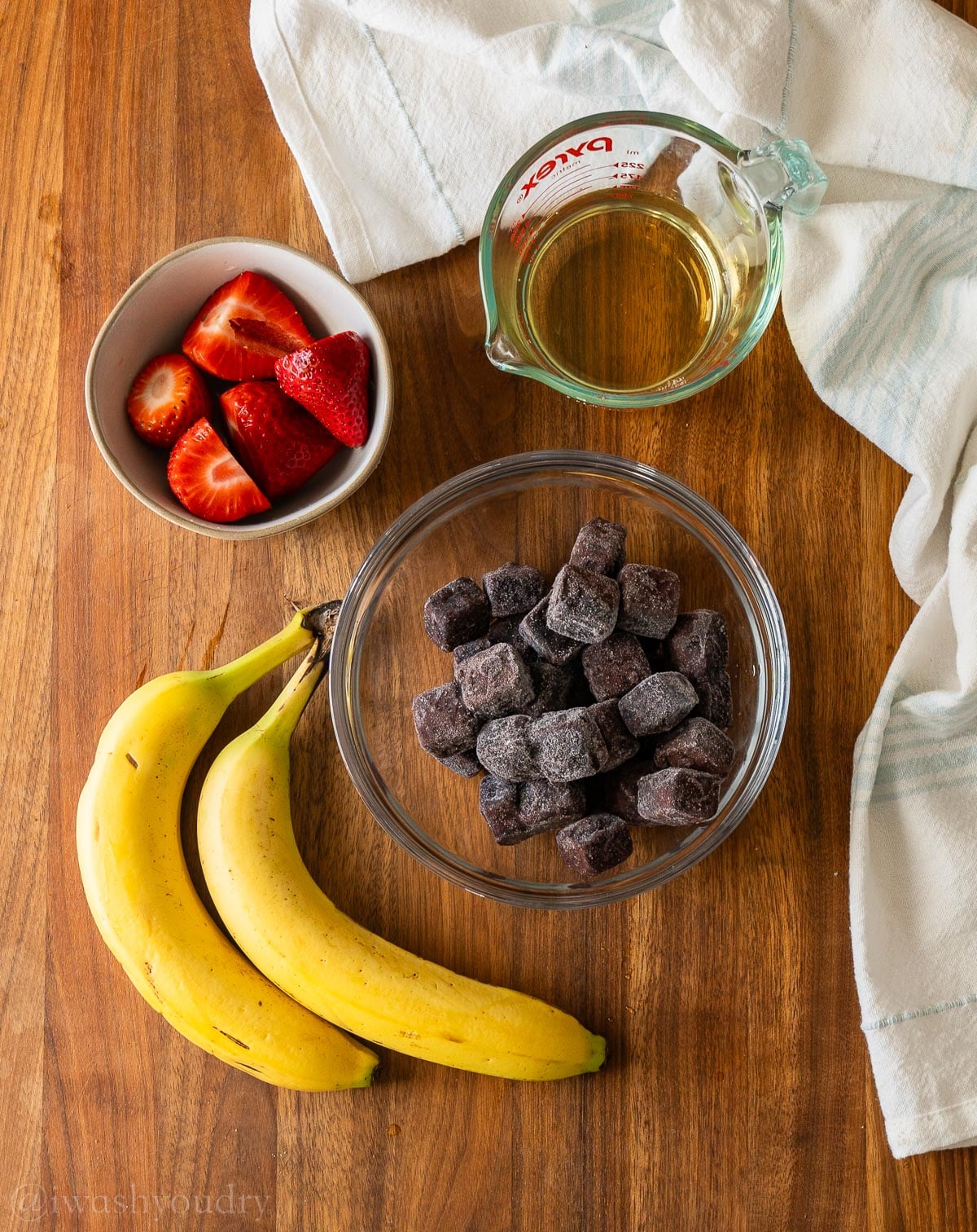 ingredients with Açai, bananas, and strawberries on a wooden surface.