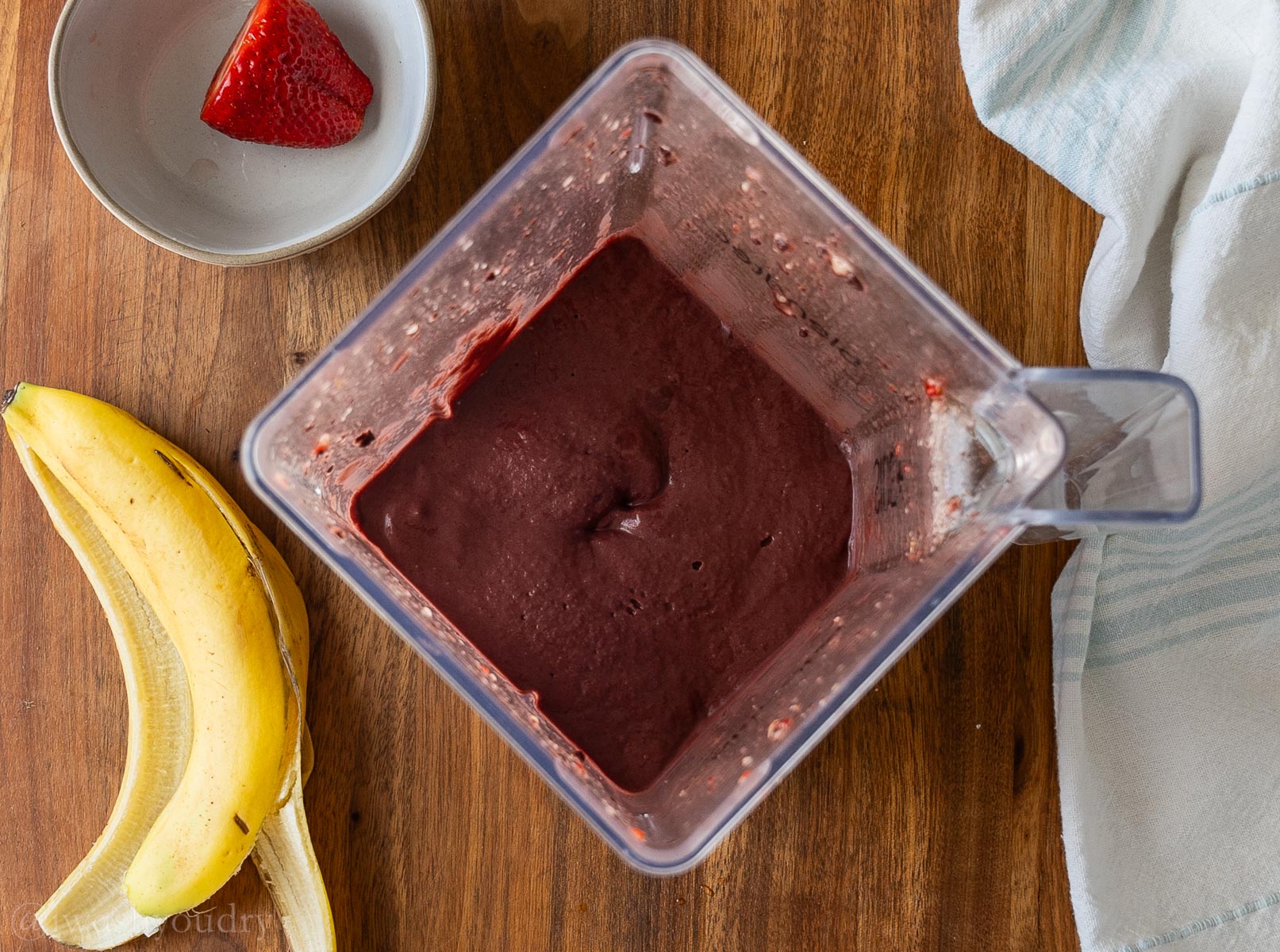 deep purple smoothie blend in blender with banana peel next to it.