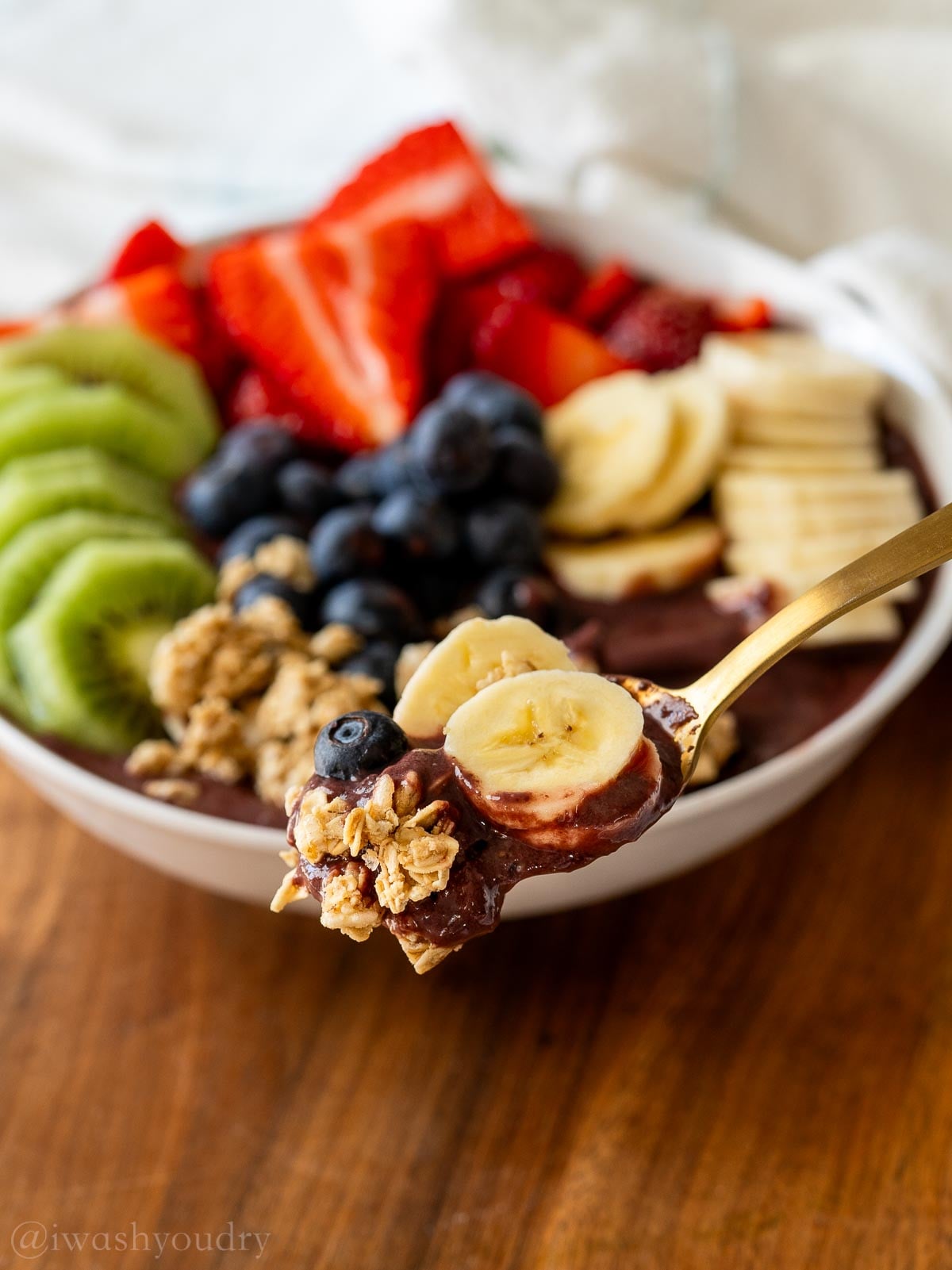 spoonful of smoothie bowl with acai, banana, granola and blueberry.