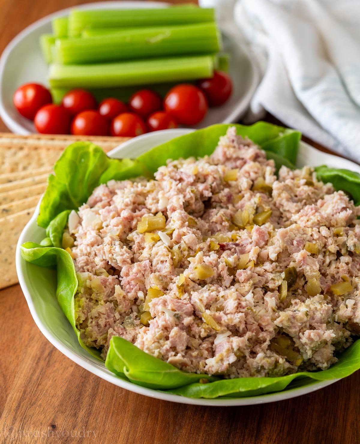 chopped ham salad in a white bowl on top of a bed of baby lettuce.