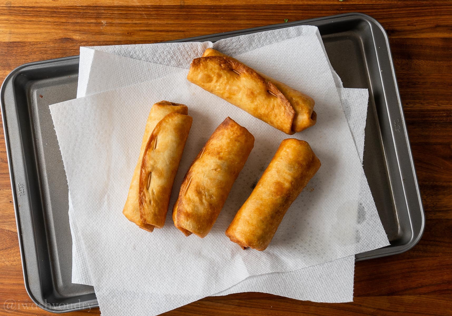 fried egg rolls on a paper towel lined baking tray.