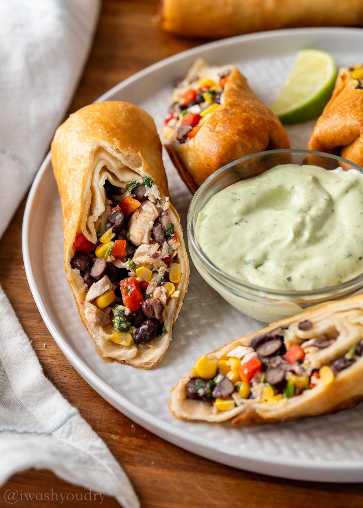 plated southern egg rolls with chicken and black beans next to a bowl of avocado ranch.