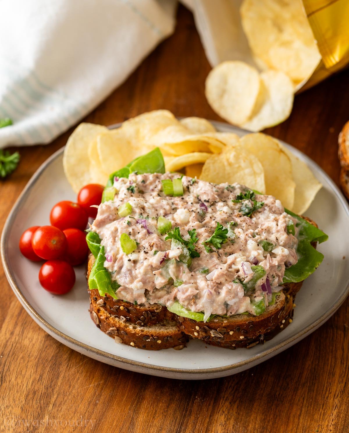 Tuna salad with celery and cottage cheese on top of bread with tomatoes on the side.