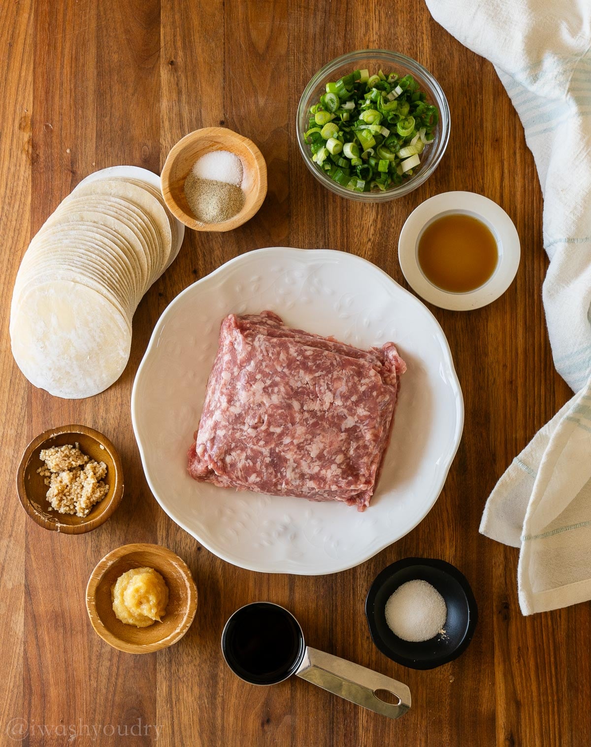 ingredients for dumplings with pork and green onions on a wooden surface.