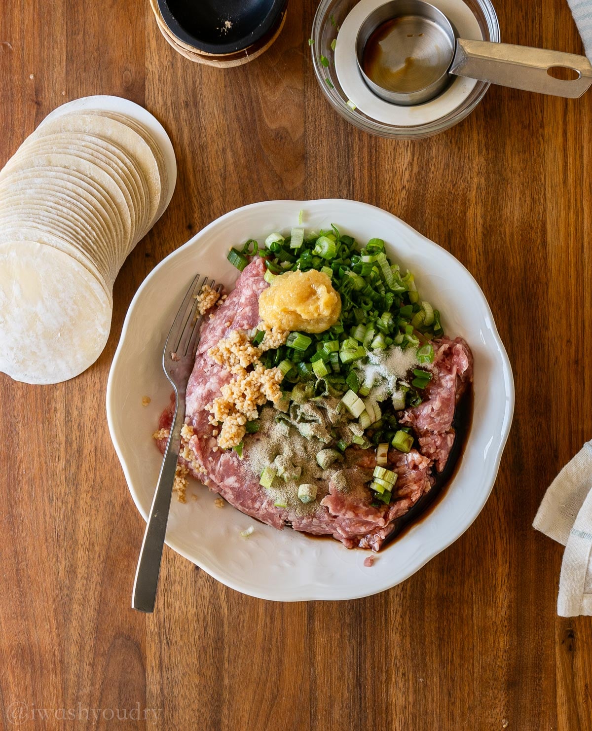 pork dumpling filling in a bowl with dumpling wrappers nearby.