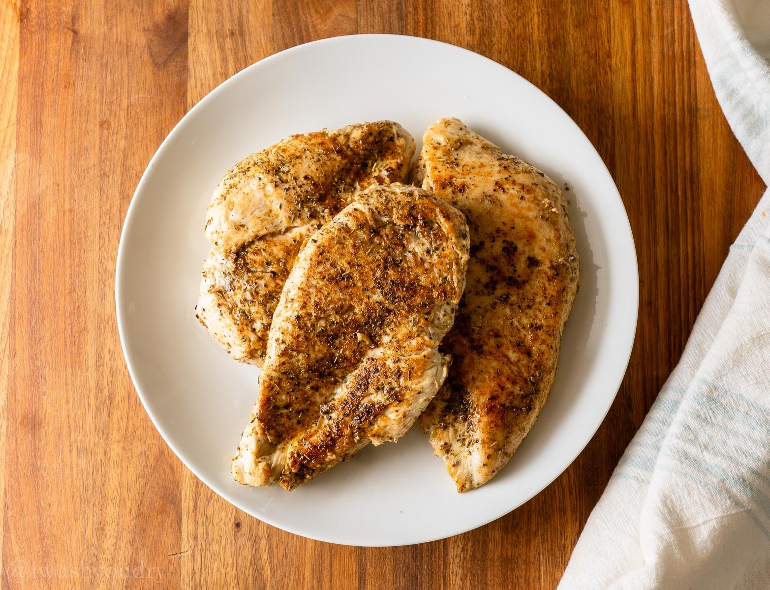seared chicken breast on a white plate.