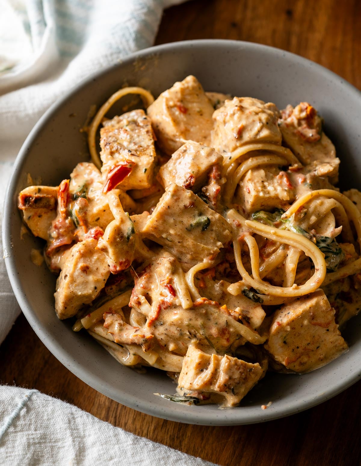 bowl of creamy tuscan chicken with pasta and sun dried tomatoes.