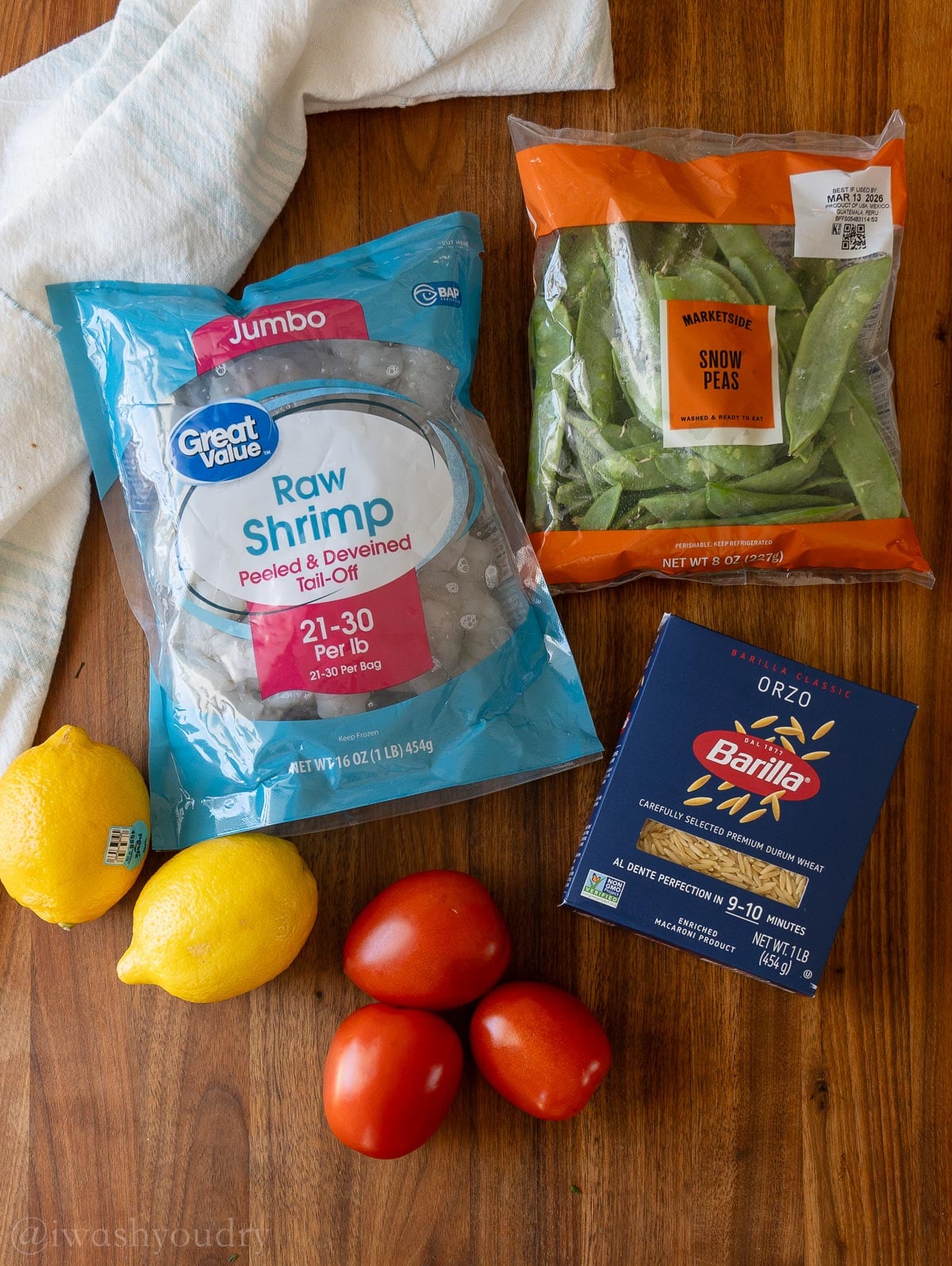 ingredients located on a wooden surface with lemons, snow peas and pasta