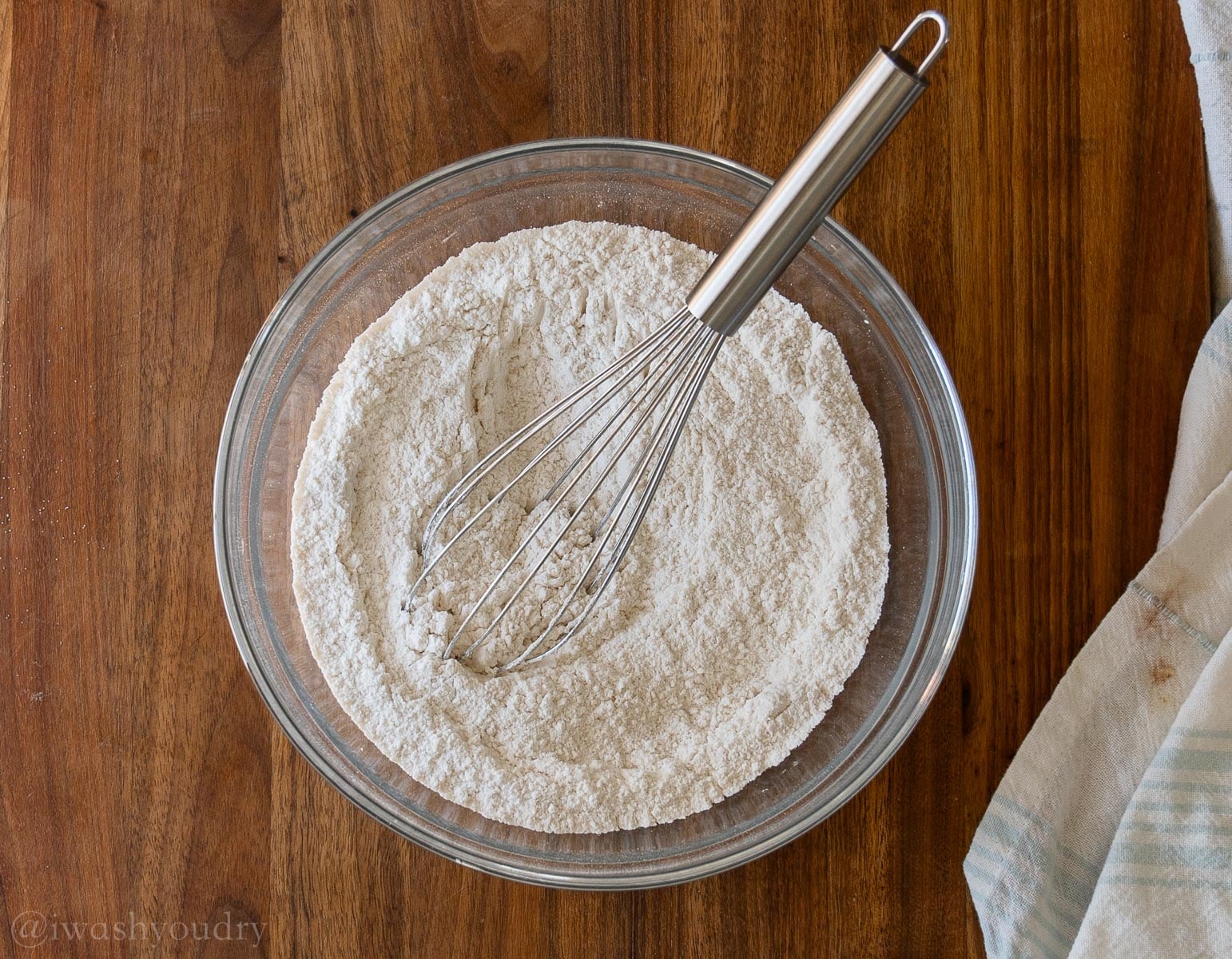 flour, baking powder and salt in a glass bowl with a whisk inside.