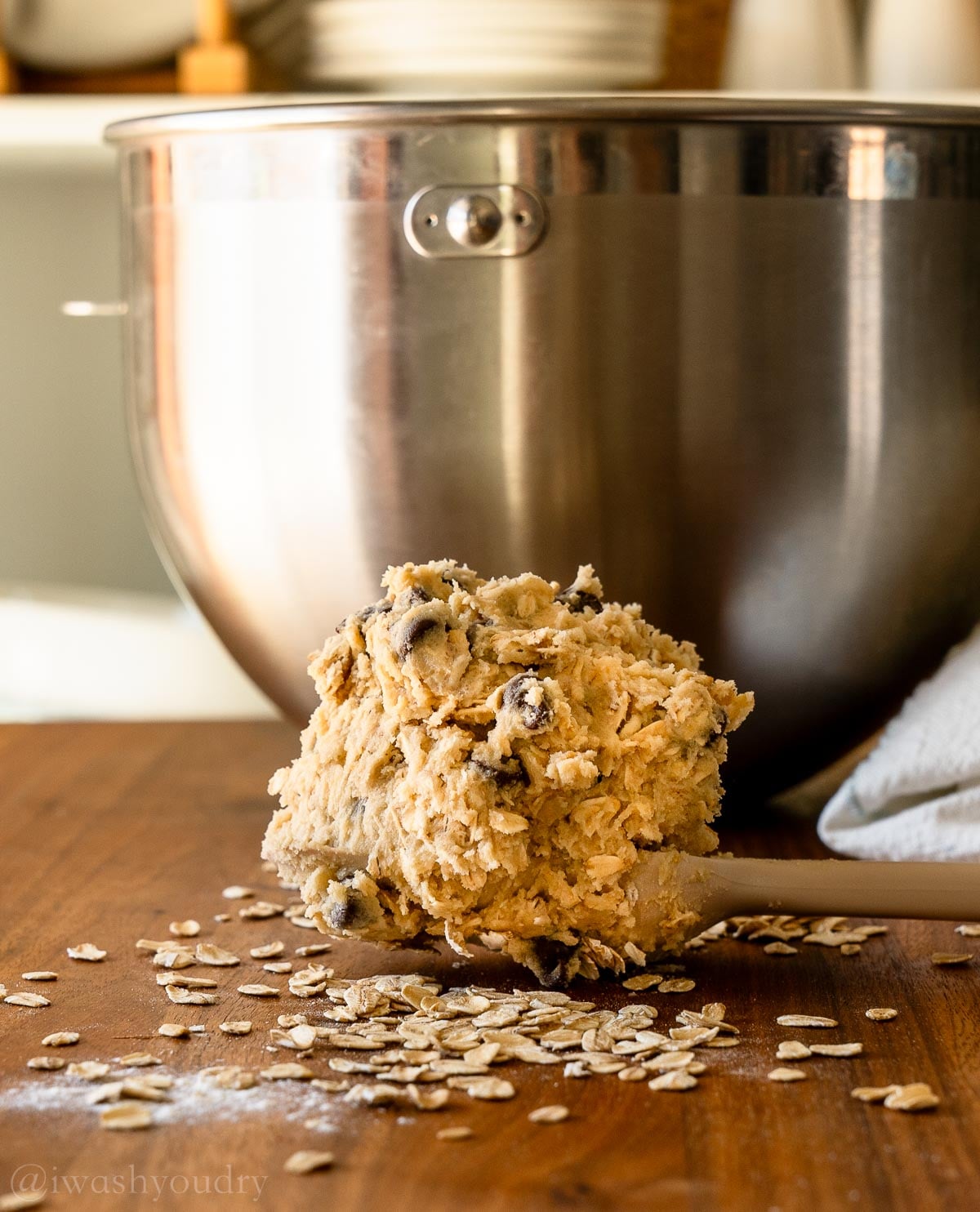spoonful of oatmeal chocolate chip cookie dough on spoon with oats surrounding it.