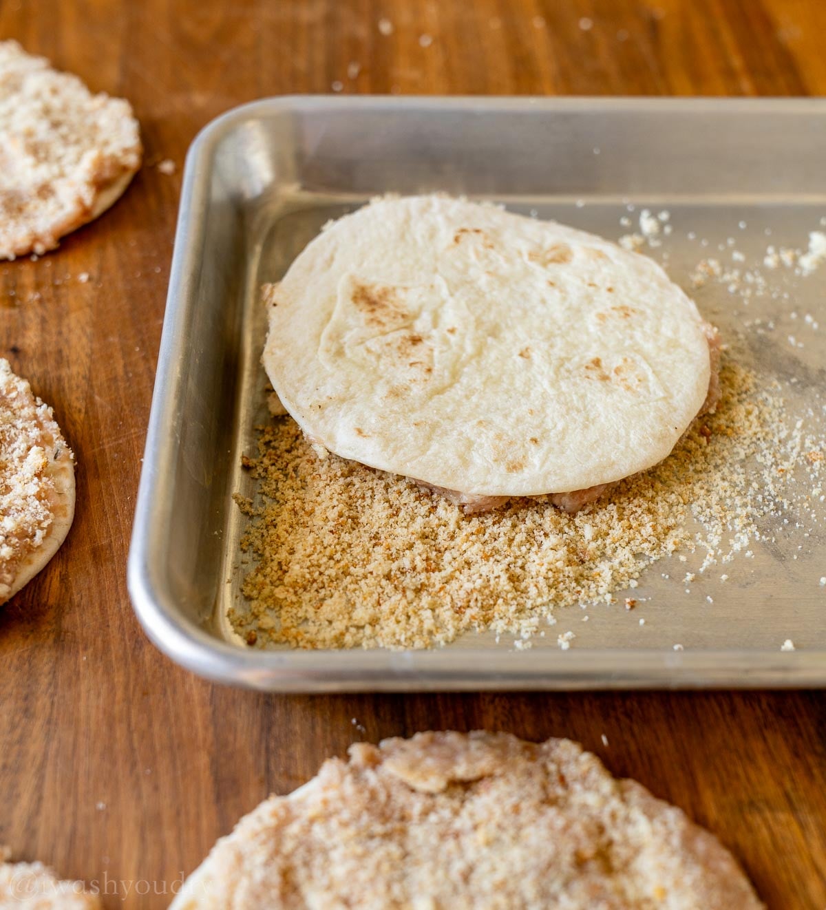 chicken tortilla in crushed croutons on metal tray.