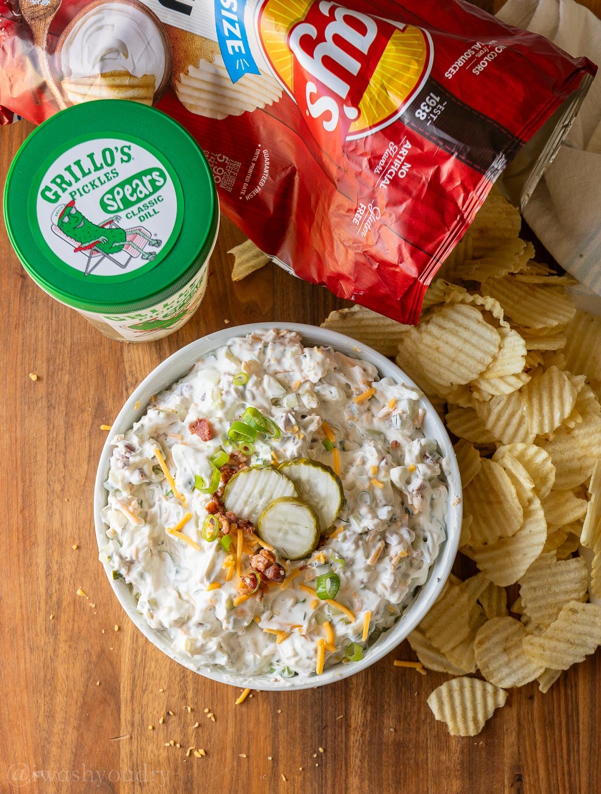 creamy pickle dip with bacon and cheddar cheese on top.