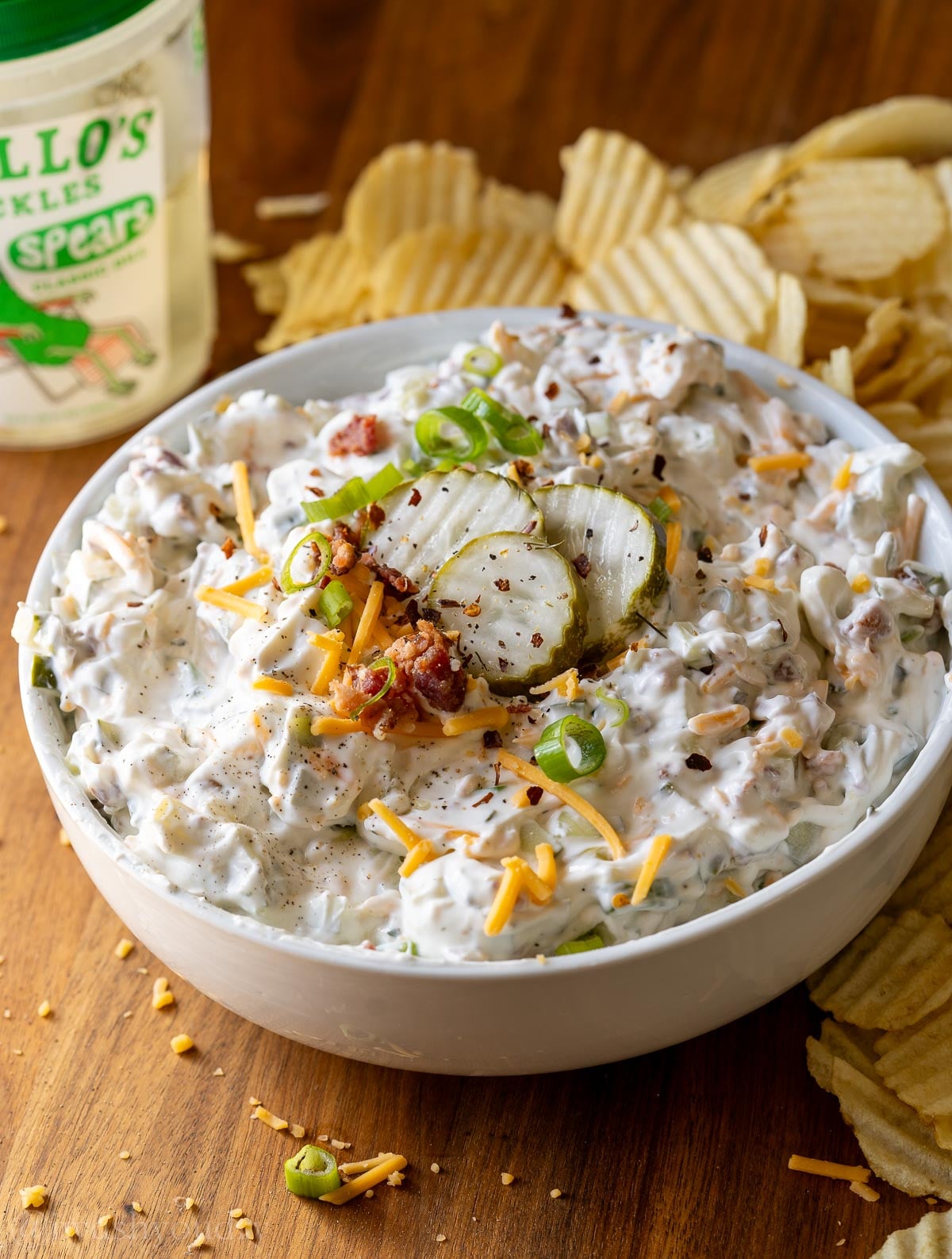 creamy pickle dip topped with sliced pickles and served with wavy potato chips.